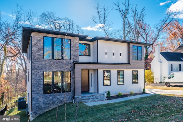 modern home featuring central AC unit and a front yard