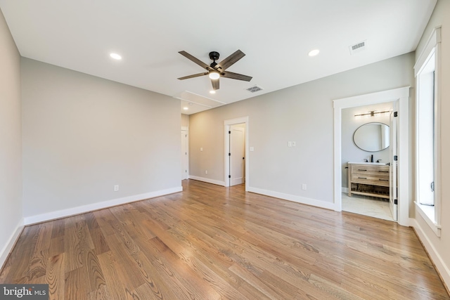 unfurnished bedroom with ensuite bath, ceiling fan, and light wood-type flooring