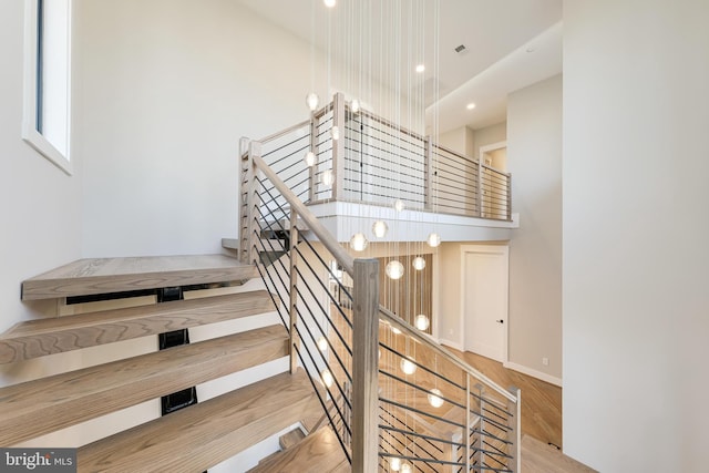 stairway featuring hardwood / wood-style floors and a towering ceiling