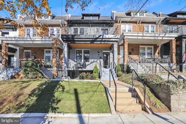 townhome / multi-family property with a porch, a balcony, and a front lawn