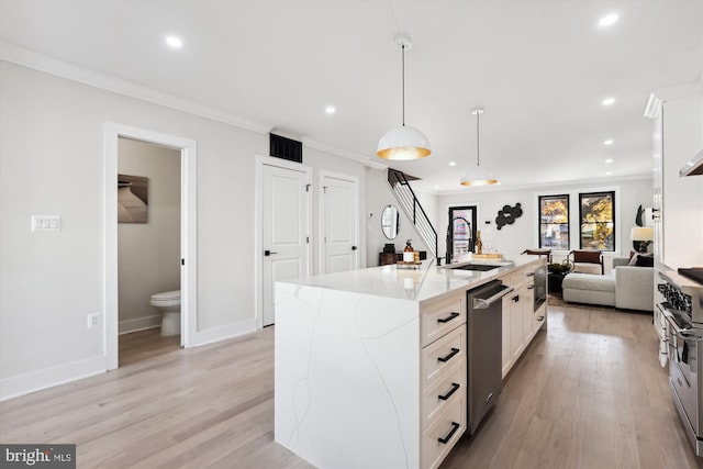 kitchen featuring light stone countertops, a center island with sink, white cabinets, and sink