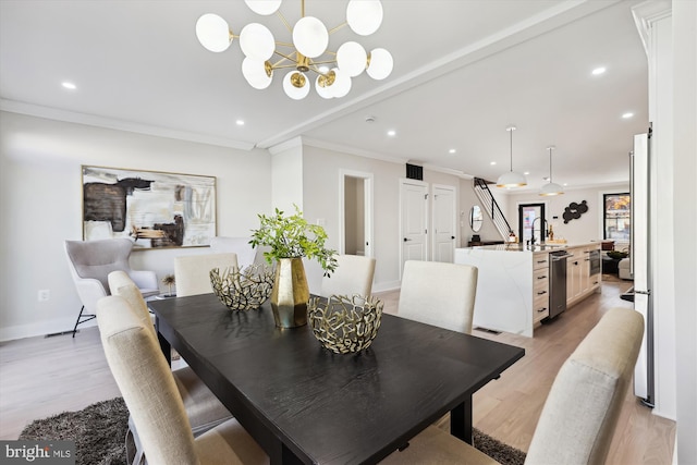 dining room with a chandelier, light wood-type flooring, crown molding, and sink