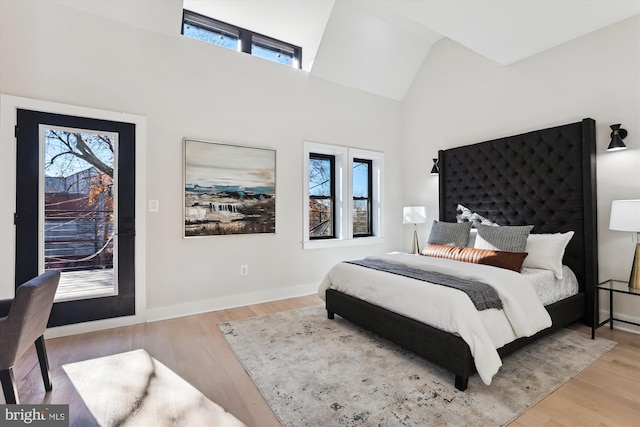 bedroom with light wood-type flooring and high vaulted ceiling