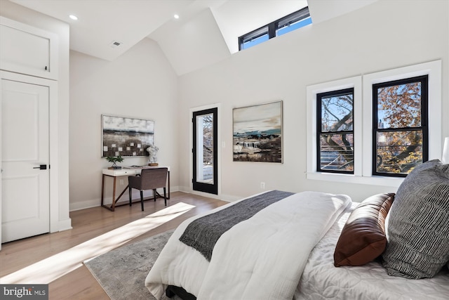 bedroom featuring high vaulted ceiling and light hardwood / wood-style flooring