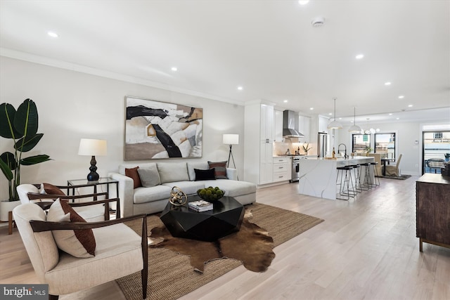 living room with light hardwood / wood-style flooring, ornamental molding, and sink