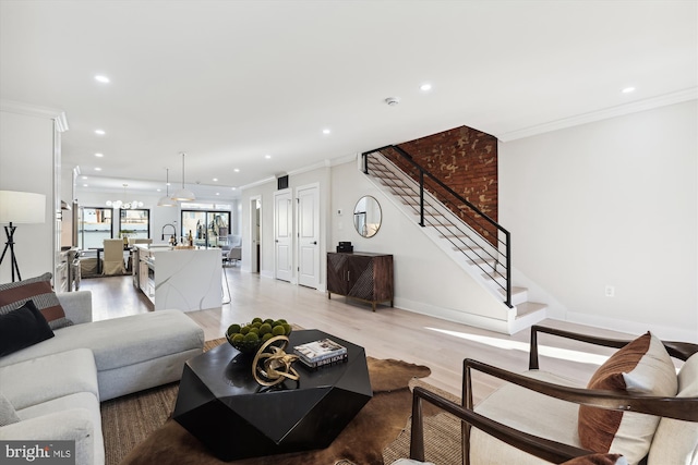 living room featuring light hardwood / wood-style floors, sink, and crown molding