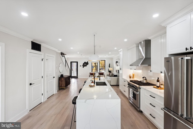 kitchen featuring sink, wall chimney exhaust hood, premium appliances, pendant lighting, and a kitchen island