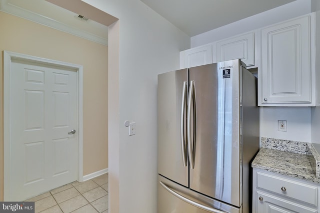 kitchen featuring white cabinetry, stainless steel fridge, light tile patterned floors, and light stone countertops