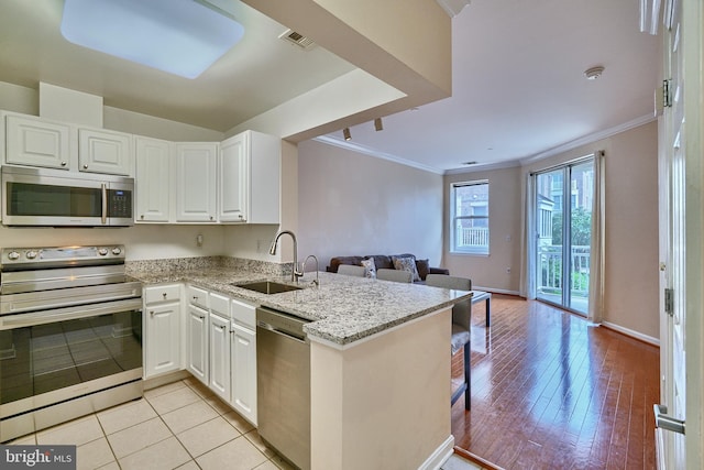 kitchen with white cabinetry, sink, stainless steel appliances, kitchen peninsula, and light hardwood / wood-style floors