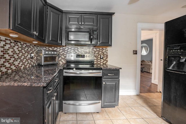 kitchen featuring black appliances, decorative backsplash, light tile patterned floors, and dark stone counters