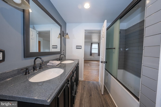 bathroom featuring wood-type flooring, vanity, and enclosed tub / shower combo