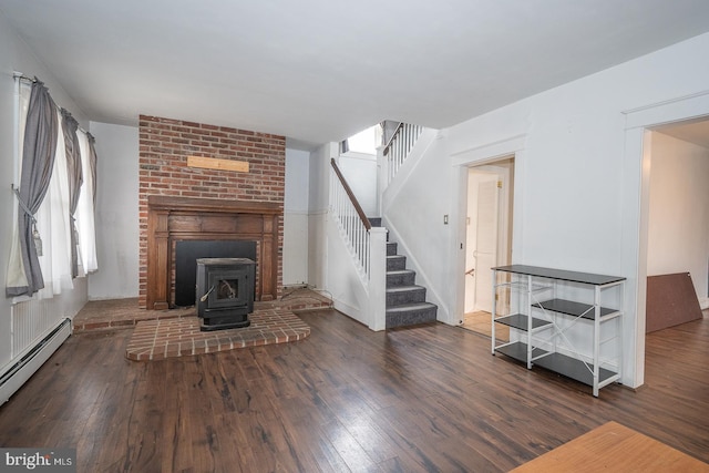 living room featuring dark hardwood / wood-style floors, a wood stove, and a baseboard heating unit