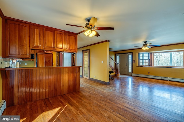 kitchen featuring a baseboard heating unit, crown molding, kitchen peninsula, paneled built in refrigerator, and wood-type flooring