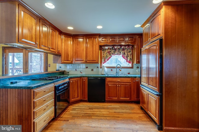 kitchen featuring tasteful backsplash, dark stone counters, sink, black appliances, and light hardwood / wood-style flooring