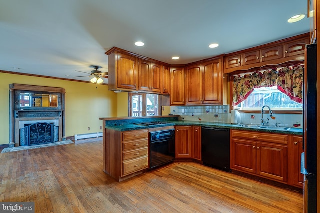 kitchen with light wood-type flooring, sink, a baseboard radiator, and black appliances