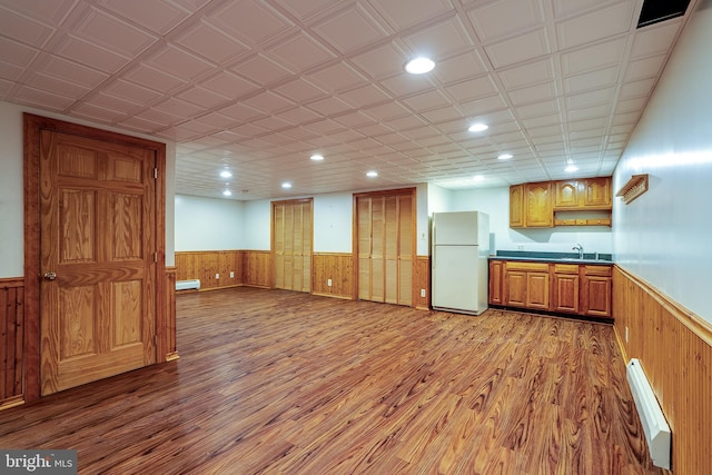 kitchen featuring light wood-type flooring, white refrigerator, a baseboard heating unit, and sink