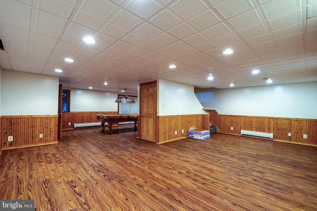 interior space featuring wood walls, pool table, dark hardwood / wood-style floors, and a baseboard heating unit