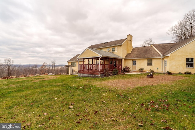 rear view of house featuring a wooden deck and a yard