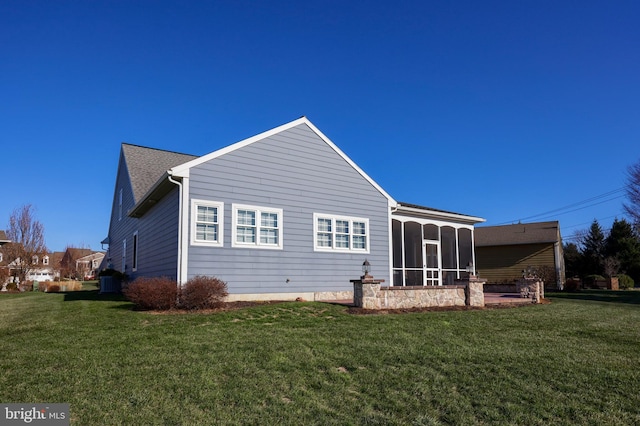 rear view of house featuring a sunroom and a yard