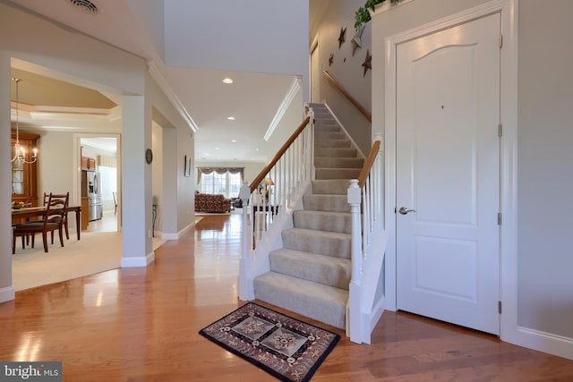 foyer entrance featuring crown molding, hardwood / wood-style floors, and a chandelier