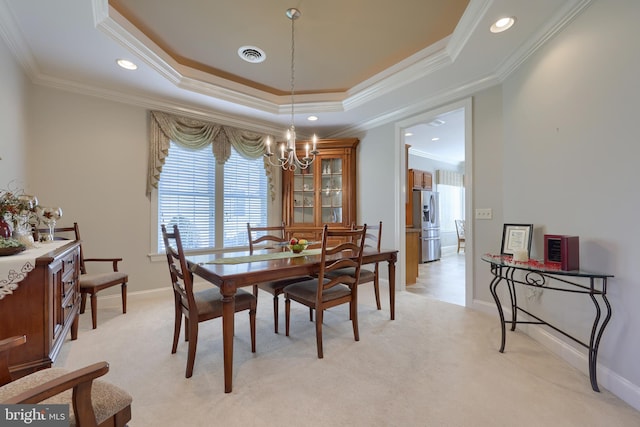 carpeted dining room featuring a tray ceiling, an inviting chandelier, and ornamental molding