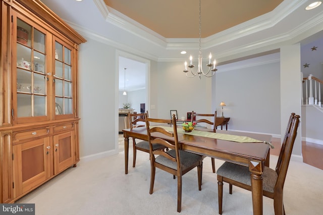 dining area with a chandelier, light colored carpet, ornamental molding, and a tray ceiling