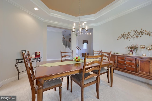 carpeted dining room with a tray ceiling, an inviting chandelier, and ornamental molding