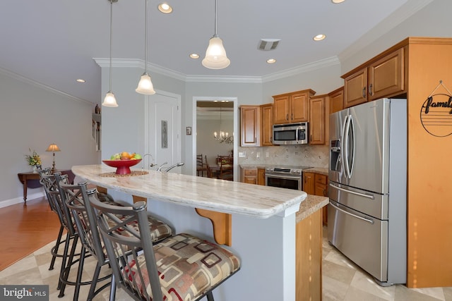 kitchen featuring a center island, hanging light fixtures, ornamental molding, appliances with stainless steel finishes, and light stone counters