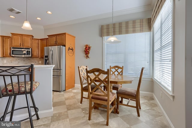 kitchen with decorative backsplash, a kitchen bar, stainless steel appliances, crown molding, and pendant lighting