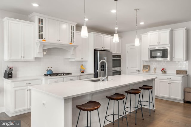 kitchen featuring white cabinetry, a center island with sink, stainless steel appliances, and sink