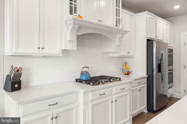 kitchen featuring appliances with stainless steel finishes, tasteful backsplash, white cabinetry, and dark wood-type flooring