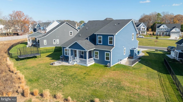 rear view of property with a lawn and a trampoline