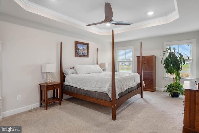 carpeted bedroom with ceiling fan, a raised ceiling, crown molding, and multiple windows