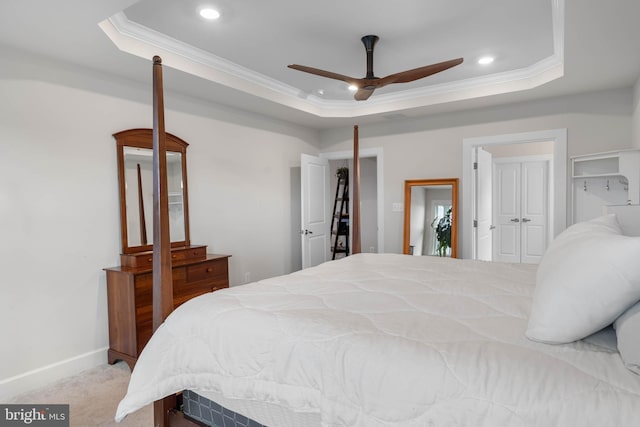 bedroom with ceiling fan, crown molding, light carpet, and a tray ceiling