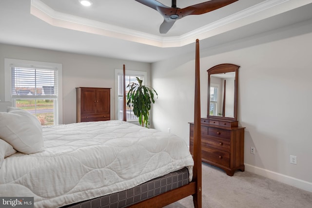 carpeted bedroom with a tray ceiling, ceiling fan, and crown molding