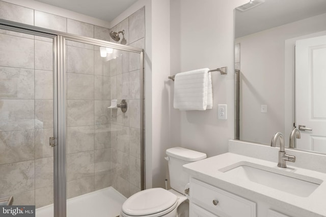 bathroom featuring vanity, toilet, and a shower with door