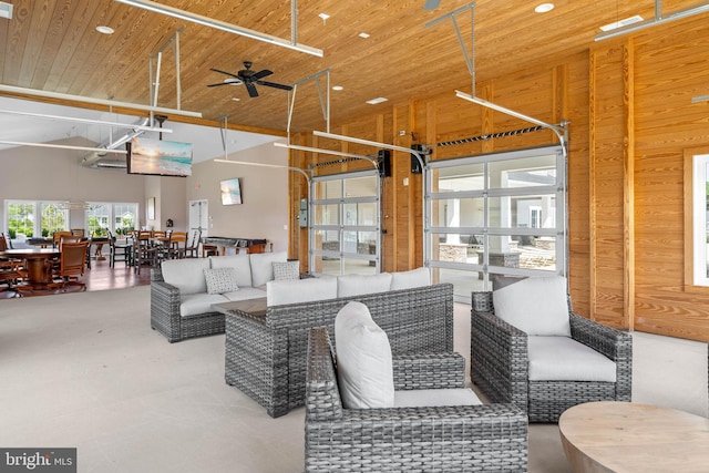 interior space with wood walls, wood ceiling, a high ceiling, and concrete floors