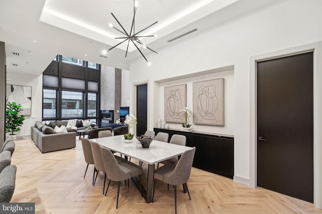 dining area with light parquet floors, a high ceiling, and a notable chandelier