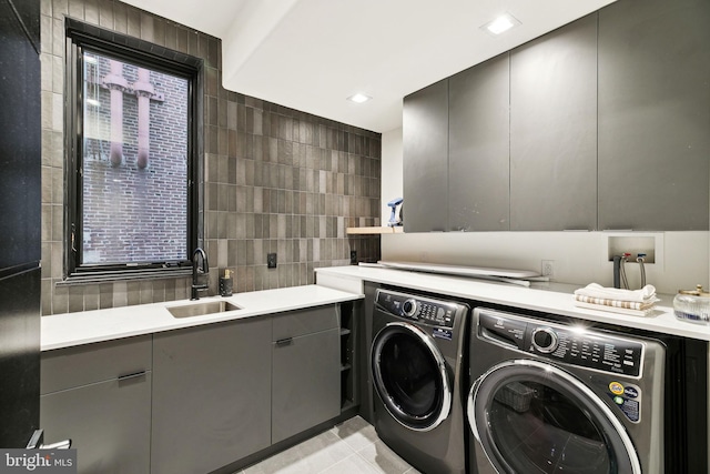 laundry room featuring light tile patterned flooring, separate washer and dryer, sink, and tile walls