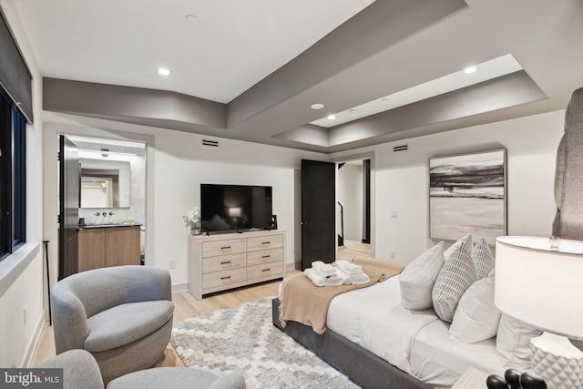 bedroom with a raised ceiling and light wood-type flooring