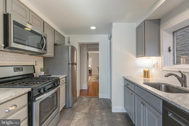 kitchen featuring backsplash, gray cabinets, sink, and stainless steel appliances