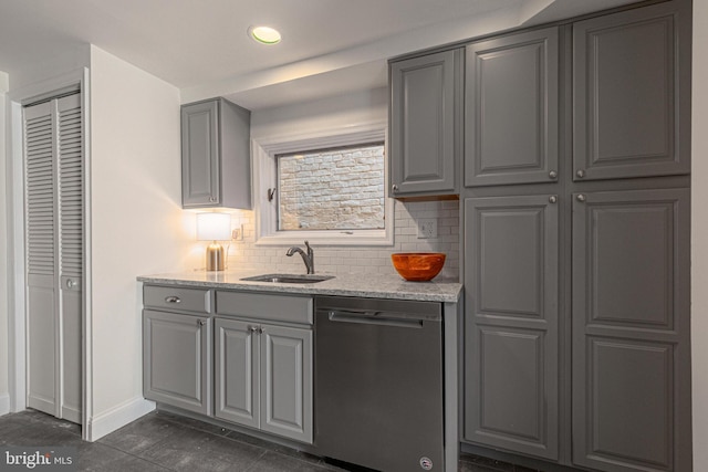 kitchen featuring decorative backsplash, light stone countertops, gray cabinetry, sink, and dishwasher