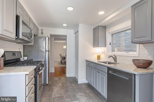 kitchen with gray cabinetry, light stone countertops, sink, and appliances with stainless steel finishes