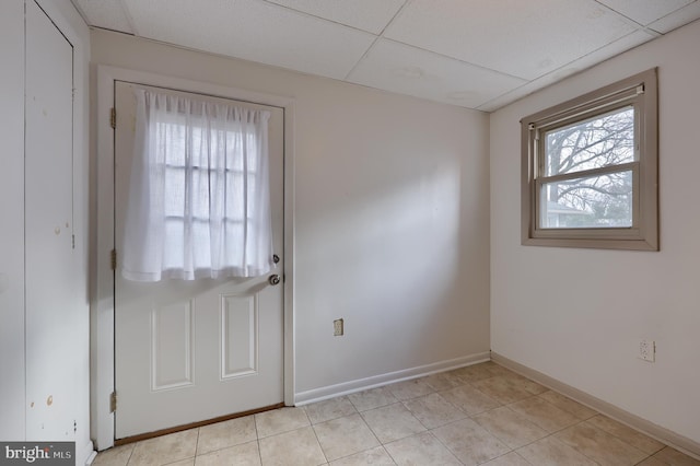 doorway to outside featuring light tile patterned floors and a drop ceiling