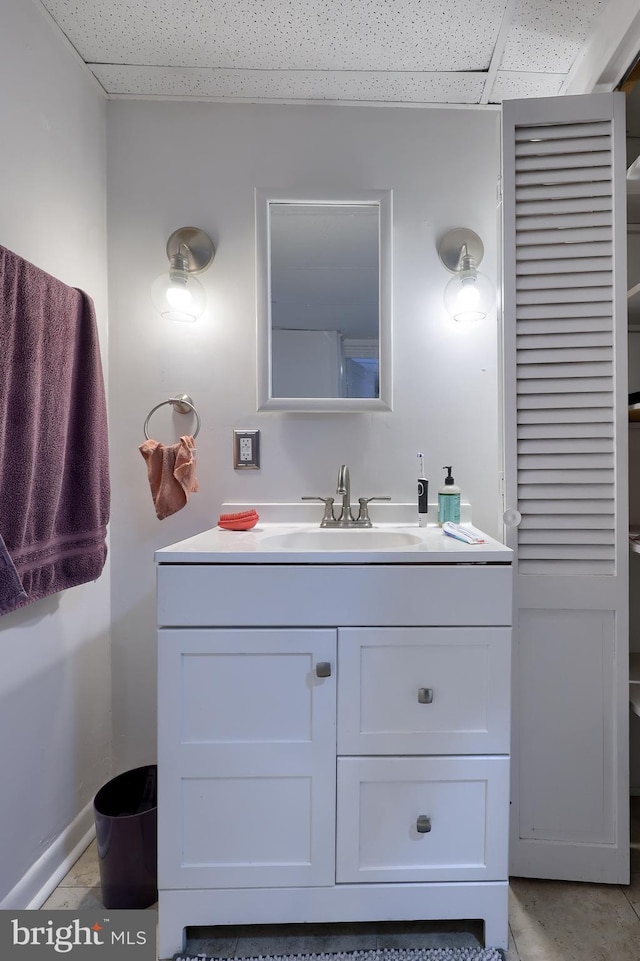 bathroom with tile patterned floors, a drop ceiling, and vanity