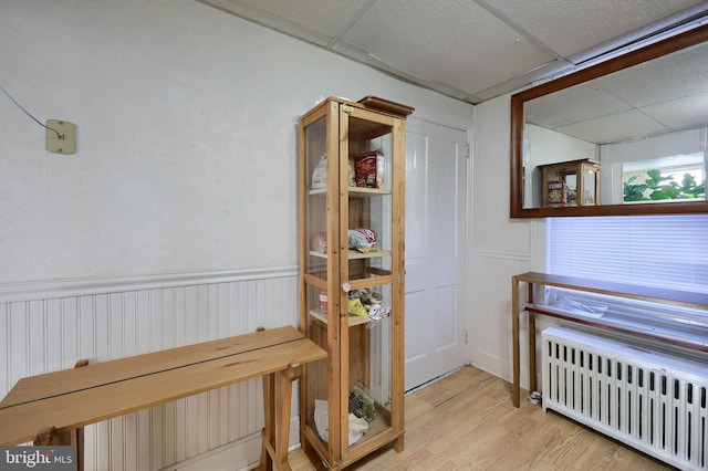 misc room with a paneled ceiling, radiator, and light hardwood / wood-style flooring