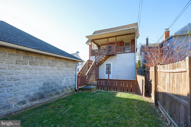 back of property featuring a balcony and a lawn