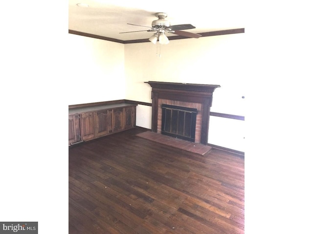 unfurnished living room with ceiling fan, a fireplace, dark wood-type flooring, and ornamental molding