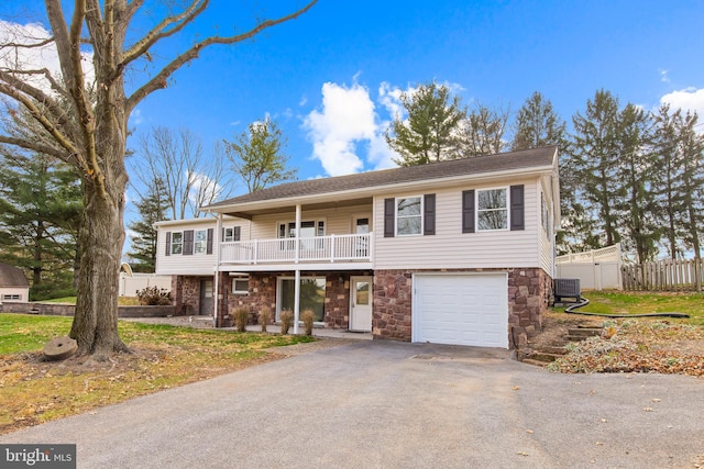 view of front of property featuring a garage, central air condition unit, and a front lawn