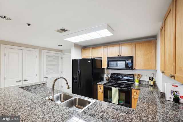 kitchen with light brown cabinetry, dark stone countertops, sink, and black appliances